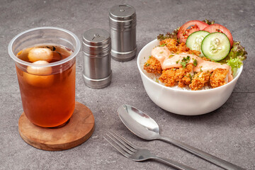Obiad składający się z rice bowl — azjatyckiego dania z ryżem, kurczakiem i warzywami oraz mrożona herbata z liczi