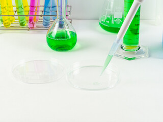 A close up of a petri dish and a micropipette tip laboratory equipment and glassware on dispaly 