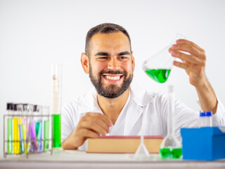 Young male scientist happily observing a liquid sample in an erlenmeyer flask in a laboratory