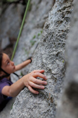 rock climber's hand close-up. child rock climber in a blue protective helmet overcomes the route in the mountains. children's sports in nature.