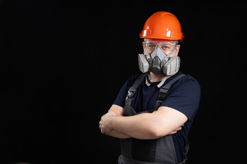 A man wearing a helmet, respirator and goggles on a black background - obrazy, fototapety, plakaty