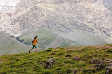 Fototapeta premium boy with a backpack on a hike against the backdrop of the mountains. child traveler with backpack, hiking, travel, mountains in the background, kids summer vacation.