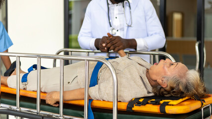 An African doctor is checking an unconscious female elderly patient when rescuer brings her to the...