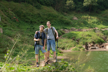 Two man hiking in the forest with backpacks and trekking poles