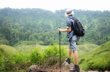 Young man with backpack hiking in the forest. Active lifestyle concept.