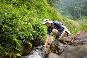Hiker in the jungle playing with water in a stream in the forest.