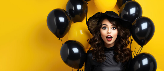Amazed young woman with bunch of air ballons keeping mouth open isolated on yellow background. Black friday sale