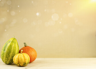 Autumn background with decorative pumpkins, sun glare. Beautiful background with yellow and orange pumpkins on a wooden background, blurry lights and copy space. High quality photo