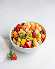 Healthy fresh fruit salad in bowl on gray concrete background. 