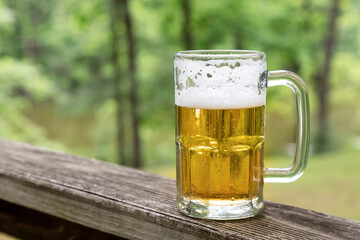 Beer in glass mug outdoors with nature background