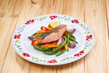 salmon steak with vegetables on wooden background