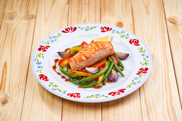salmon steak with vegetables on wooden background