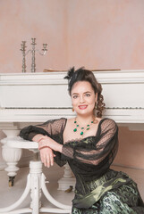 Beautiful young smiling woman wearing green medieval vintage Victorian Style dress sitting near...
