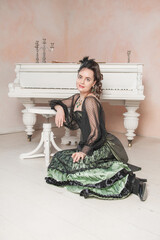 Beautiful young smiling woman wearing green medieval vintage Victorian Style dress sitting on the...