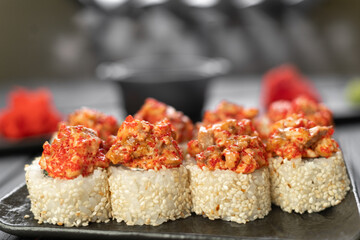 Close Up on served baked sushi rolls with eel and tobiko caviar on black slate board.