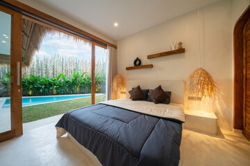 Interior design of bedroom in luxury and modern style pool villa feature a pool view, green garden, sunbed or sunlounger on pool terrace, blue cushion on bed and hanging lamp and sliding door