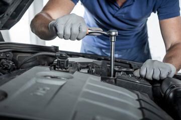 Mechanic repairing a car breakdown with torque wrench at workshop or dealership. Maintenance and...