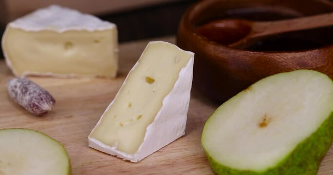pour honey on the delicious soft cheese with white mold close-up, pieces of cream cheese with white mold