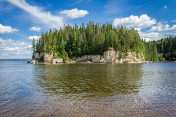 Rocks with a coniferous forest, a large river against the background of clouds in summer. Russia,...