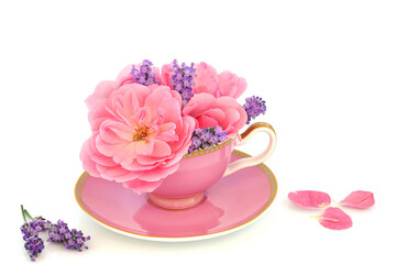 Rose and lavender flowers in tea cup with petals on white. Surreal fun food medicinal herbal medicine composition. Flowers have adaptogen health benefits.
