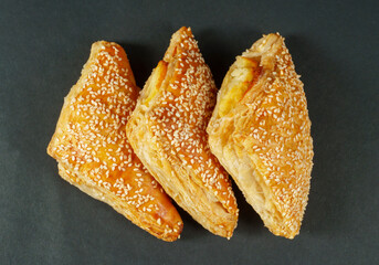 burekas - a puff pastry pie with cheese coated with sesame seeds.on black background.Top View
