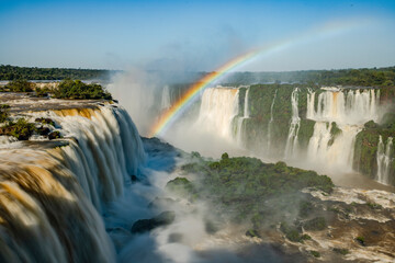Fototapeta premium Perfect rainbow over Iguazu Waterfalls, one of the new seven natural wonders of the world in all its beauty viewed from the Brazilian side - traveling South America - long exposure