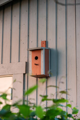 Red painted bird house on the side of a garage.