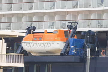 A forklift lowers a lifeboat at a huge cruise ship