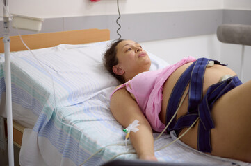 Pregnant birthing mother woman has contractions, checks the heartbeat and pulse of her baby, using...