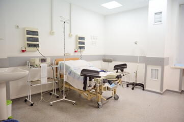 Empty delivery room with bed and medical equipment in maternity ward at hospital. Childbirth. Delivery. Labor concept