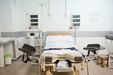 Hospital bed, obstetric chair in delivery room with electrocardiograph for monitoring heartbeat of future newborn baby