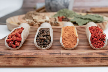 different types of spices in wooden spoons on a wooden board cayenne, pepper, cinnamon,