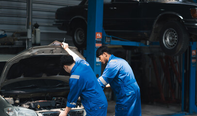 Fototapeta na wymiar Asian mechanic repairing a car in auto repair shop.