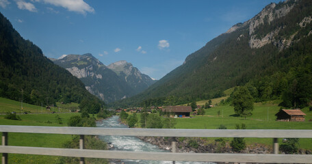 Fototapeta na wymiar Village next to river near mountains Alps Switzerland