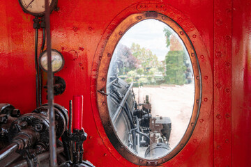 View from the window of the red-painted driver's cab of an old steam locomotive