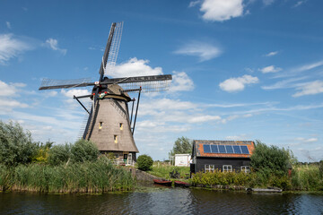 iconic smock ground sailer windmill in Kinderdijk Netherlands. Landmark buildings originally made to pump water out of low land polder to preserve land reclaimed from the sea. Solar sun panels on shed - 636694208