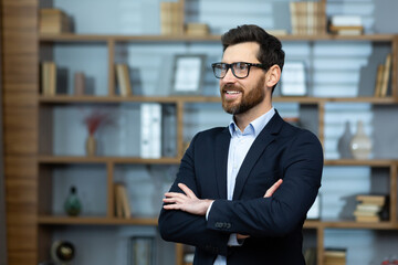 Portrait of successful mature boss, senior businessman in glasses and business suit looking away...
