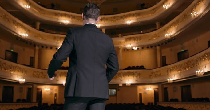 arrogant selfish actor clapping hands, standing with raised arms, empty seats in background Nobody has come to the concert, failure Covid-19 Bad unsuccessful performer playing in room without audience