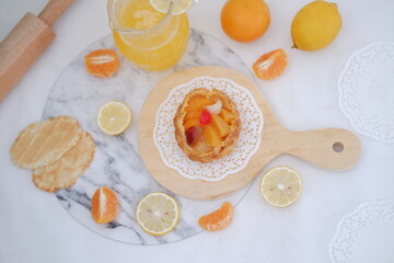 Homemade lemon tart with fresh fruit and orange juice on white background