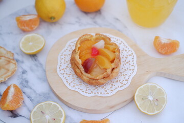 Homemade lemon tart with fresh fruit and orange juice on white background