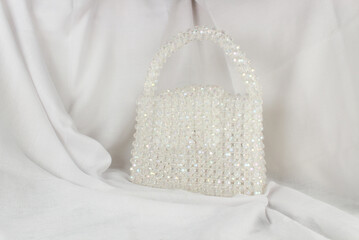 White purse bag made with beads. Handmade white purse bag on gray fabric.