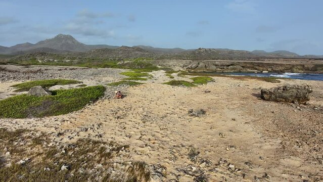 A woman on the raw coast of an island in the Caribbean