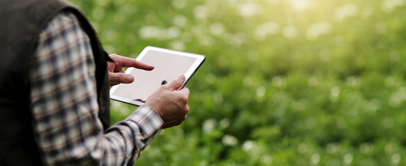 Cropped shot of farmer's hands hold and use digital tablet to analyse and check the growth and...