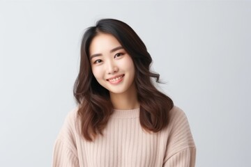 Obraz premium Medium shot portrait of a Chinese woman in her 20s in a white background wearing a cozy sweater