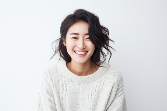 Lifestyle portrait of a Chinese woman in her 20s in a white background wearing a cozy sweater