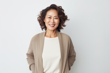 Lifestyle portrait of a Chinese woman in her 40s in a white background wearing a chic cardigan