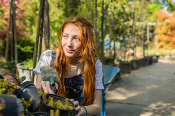 Fototapeta na wymiar Young ginger florist taking care of her plants
