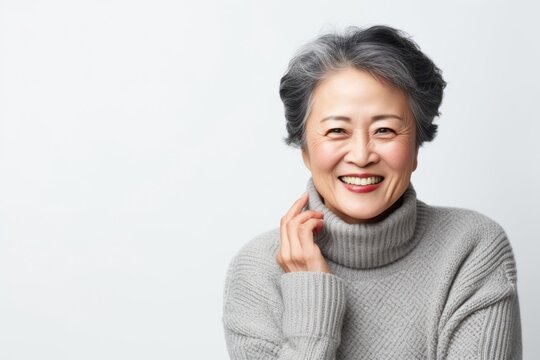 Medium shot portrait of a Chinese woman in her 50s in a white background wearing a cozy sweater