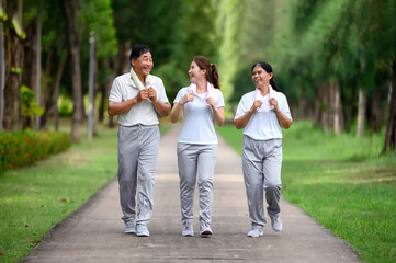 Asian Seniors and Daughter Jogging and Relaxing in the Park, Family Bonding in Nature, Seniors and Family Enjoying Exercise and Relaxation in the Green Park, Health Care and Family Bonding Concept