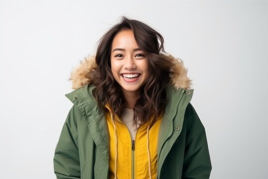 Medium shot portrait of a Indonesian woman in her 20s in a white background wearing a warm parka